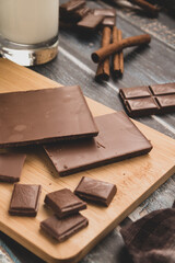 milk dark chocolate tiles on wood cutting board, wooden background