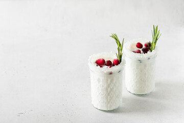 White cocktail with coconut milk, cranberry and rosemary alcoholic or moctail on white background