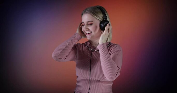 Eine attraktive Blondine mit kurzen Haaren hat die Kopfh&ouml;rer an, h&ouml;rt die Musik, singt und tanzt dabei.