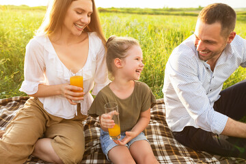Laughing family drinking orange juice from glasses