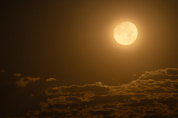 Beautiful night sky. The full moon illuminates clouds.  Nature background