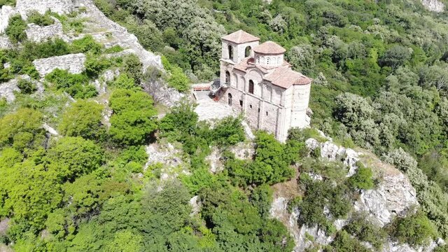 Medieval Fortress on a hill in eastern Europe, Bulgaria. Bulgarian antique and heritage stronghold fortification on a rock. Aerial video of a holy place and monastery. Tourist place with forest. Drone