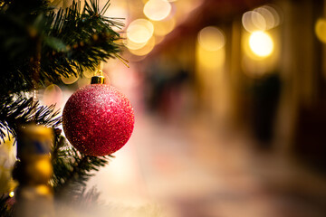 Close-up view of red sparkle ball as decoration hanging on the branches of a Christmas tree and sparkling.