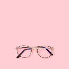 Eyeglasses on a pink pastel background. Minimalistic concept with place for text.