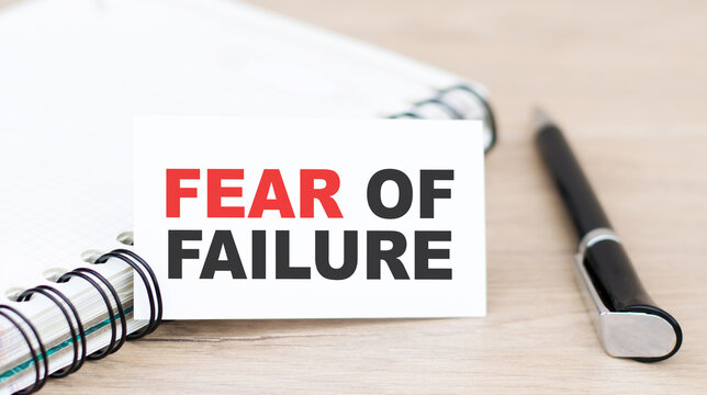 text fear of failure on a white card lying near a notepad on the table