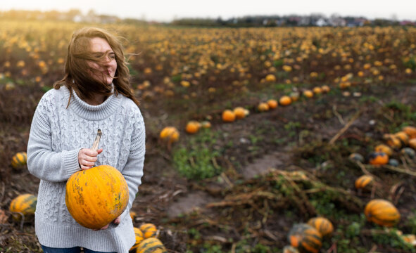 Woman With A Pumpkin On A Pumpkin Field