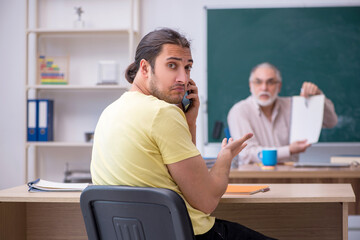 Old teacher and young male student in the classroom