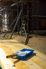 Paint roller and paint bath with white paint on the construction site of a house