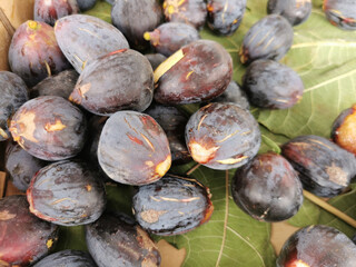 Cut figs on a fig leaf on a background of whole figs in the boxes for sale. Ripe figs in boxes for sale in the spanish market