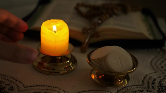 faithful puts a candle next to the communion hosts in the twilight