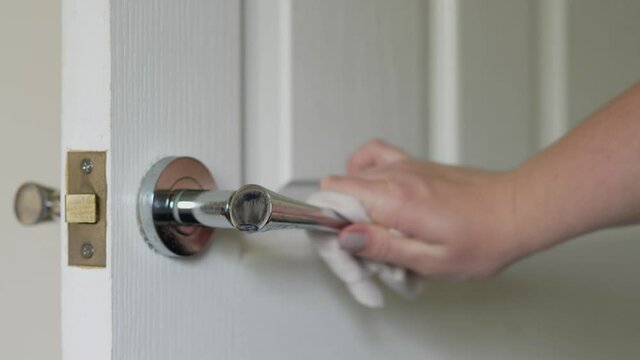 Close up of Woman cleaning door handle with an antiseptic disinfectant spray and wet wipe