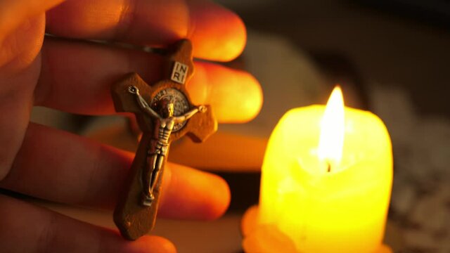 cross with Christ Jesus in twilight illuminated by candle light
