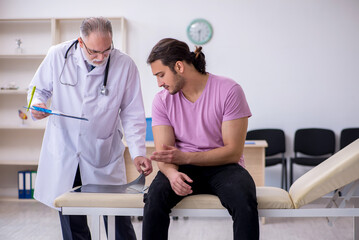 Old doctor radiologist examining young male patient