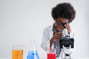 African american child boy student is learning and test science chemical by looking to microscope...