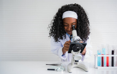 African american child girl student is learning and test science chemical by looking to microscope