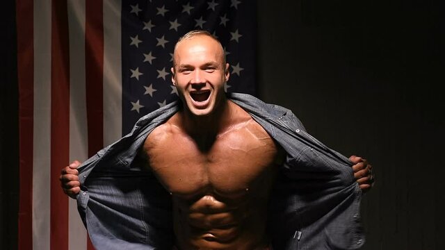 Good looking sporty young man rips his shirt off. Fitness and bodybuilding concept. American flag 

