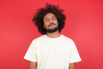Fototapeta na wymiar Close up studio shot of handsome young mixed race man model with curly dark hair looking at camera with charming cute smile while posing against white blank copy space wall for your content