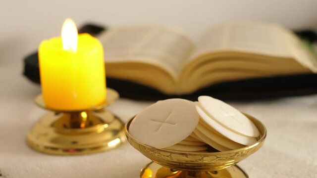 communion hosts lit candle and holy bible 
