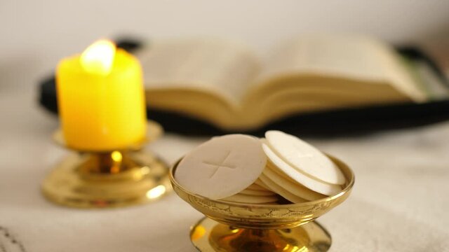 communion hosts lit candle and holy bible 