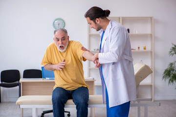 Old injured man visiting young male doctor chiropractor