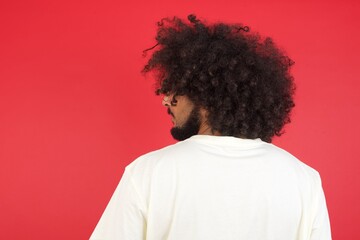 The back view of a guy wearing casual clothes standing against gray wall. Studio Shoot.