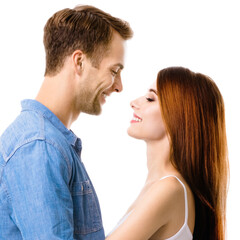 Profile side of smiling happy couple. Portrait image of standing close and looking at each other models in love studio concept, isolated over white background. Man and woman posing. Square composition