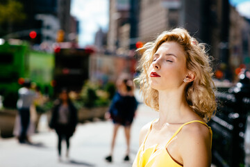 Portrait of a young woman enjoying sun and taking a breath in the city