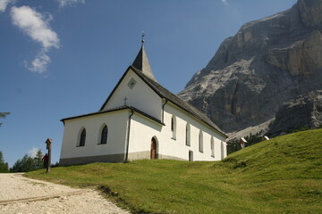 Fototapeta na wymiar panoramic view of the meadows and mountains of the sella group in alta badia with old church. Summer La Crusc Santa Croce Sanctuary