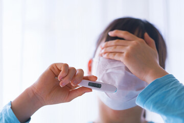 Japanese woman measures fever with thermometer