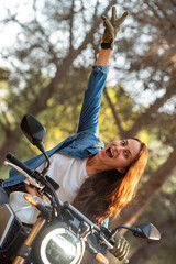 Fototapeta na wymiar A cheerful young woman with loose, brown hair on a big bike.