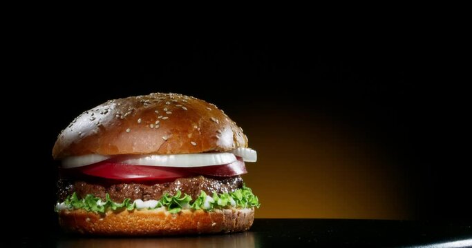 Yummy juicy burger with fresh ingredients rotating in front of camera. Delicious hamburger with grilled beef steak served on chef's table 4k footage close up shot