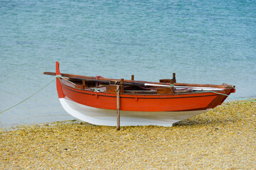 red wooden fishing boat dries up on the seashore