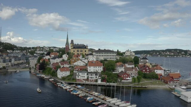 Sailboats Anchored On The Woode Jetty With The Arendal City Under The Bright Blue Sky In Agder County, Norway.  - aerial drone