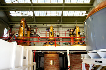 Copper stills and a mashtun in a still house of a Scottish whisky distillery