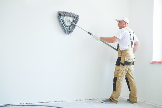Painter works with triangle drywall cleaning tool. Surface preparation for painting