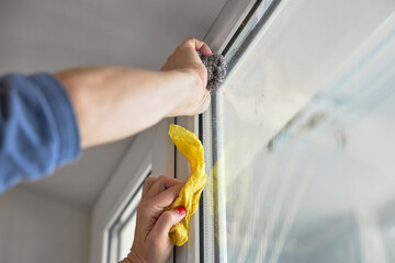 Woman washes a glass of white plastic window