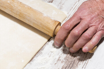 the process of rolling dough. man's hands and rolling pin, top view