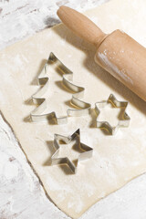 the sheet of dough on the table, cookie cutters and rolling pin, top view vertical