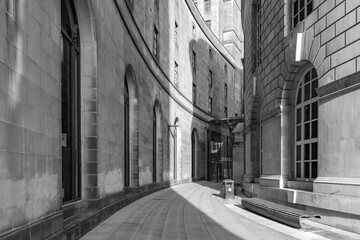 Black and white photo of the curve of library walk in Manchester with the late evening sunlight casting into the shot. 
