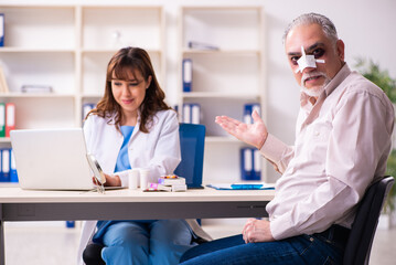 Obraz premium Old man visiting young female doctor for plastic surgery