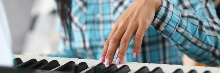 Close-up of female hands learning to play on modern synthesizer. Musician playing piano with notes....