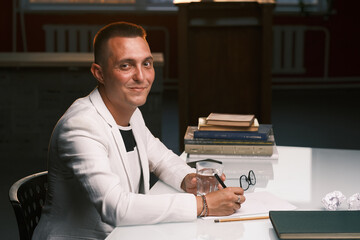 A businessman of 30-35 years old in a white jacket signs important documents.