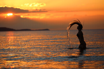 Obraz premium Młoda dziewczyna pozuje do zdjęć w trakcie zachodu słońca