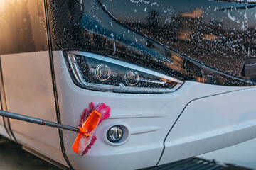 Young man washing bus using high pressure water. Selective focus.