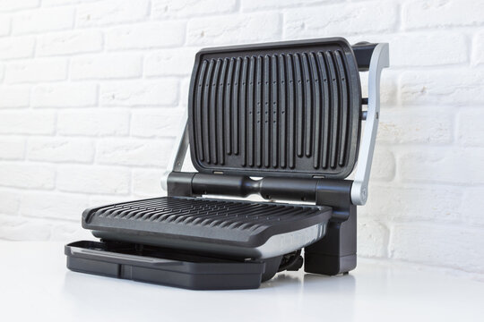 Open empty electric grill. Barbecue for home use on white kitchen background.