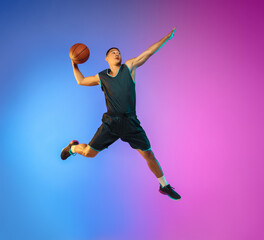 Winner. Young basketball player in action, motion in high jump on gradient background in neon....