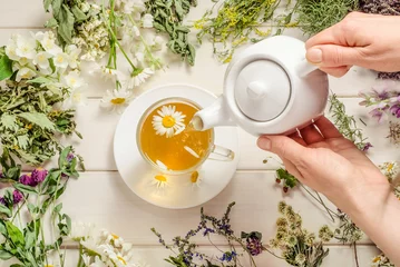 Plexiglas foto achterwand Woman pouring chamomile herbal tea on white wooden background © Victoria