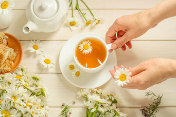A woman brews herbal tea with chamomile.