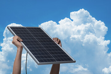 Hand holding a solar panel on blue sky background,alternative clean green energy concept