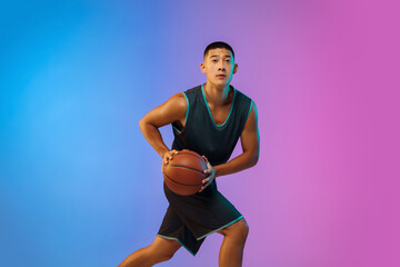 Winner. Young basketball player in action, motion on the run on gradient background in neon....
